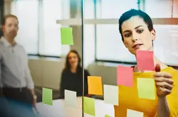 female posting sticky note and people in the background