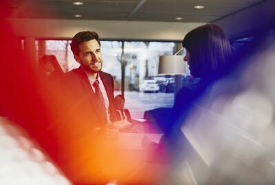 Business man receiving an entrance pass at a reception desk. Primary color: red.