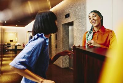 Smiling hotel receptionist helping a guest. 