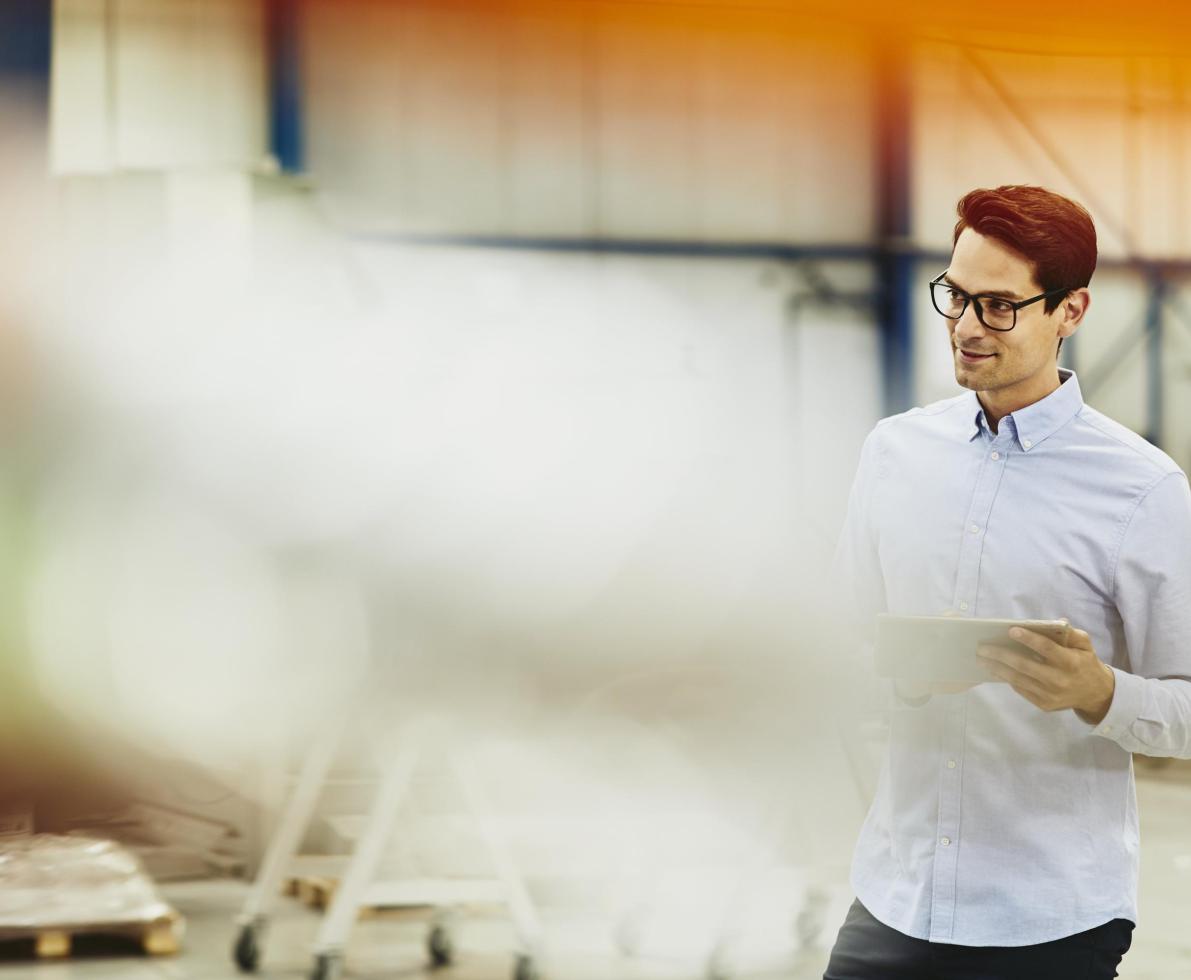 Male worker in a tech environment. Holding papers. Wearing glasses. Factory/logistics. Solid white shirt. Primary color cream. Secondary color yellow/orange. ένα εργαζόμενος σε μία αποθήκη