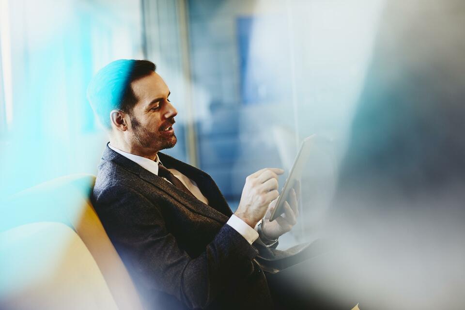 Man in suit with tablet. Primary color: blue.